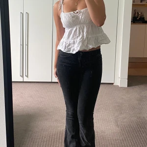 Vit ärmlös topp med volang - Säljer en söt vit ärmlös topp med volangdetaljer och knytband på axlarna. Säljer även de svarta bootcut jeansen från zara för 100. Köp båda tillsammans för 150💕