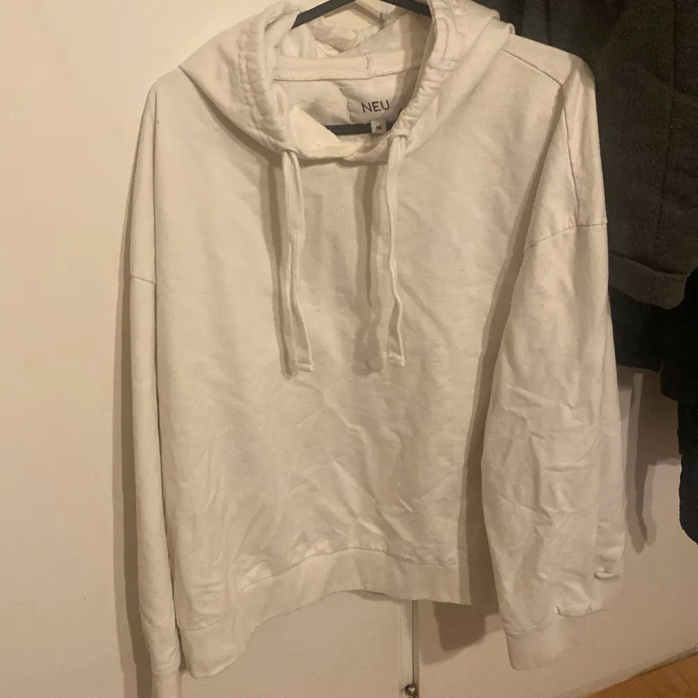 Säljer en stilren vit hoodie från NEU i storlek M. Den har en klassisk design med dragsko i huvan och långa ärmar. Perfekt för en avslappnad look.. Neuletakit & Villapaidat.