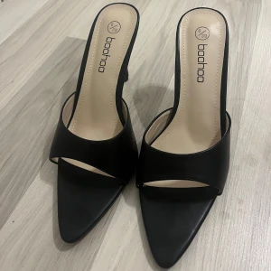 Svarta klackskor från Boohoo - Såå snygga svarta klackskor från Boohoo med spetsig tå och öppen häl. Perfekta för en elegant look. Aldrig använda beställde tyvärr fel storlek, köpte för 486 kr 