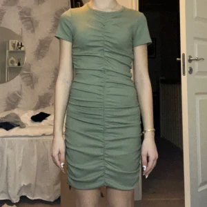 Grön ribbad klänning - Snygg grön klänning med ribbad textur och rynkade detaljer på sidorna. Kortärmad som ger en stilren look. Perfekt nu inför våren och sommaren! Den kommer från H&M och kostade 200 kr i butik. Den är använd runt 2 gånger så den är i väldigt bra skick! Så snygg och skön!! 😍