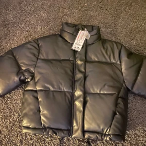 Svart pufferjacka - Snygg svart pufferjacka från newyorker . Jackan har en hög krage och dragkedja framtill. Perfekt för kyliga dagar med sin quiltade design och croppade passform(helt ny med prislapp). Säljer eftersom jag hann inte lämna tillbaka den 