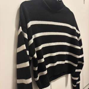 Svart och vit randig tröja från hm - Säljer en snygg svart och vit randig tröja från hm Tröjan har en hög krage och långa ärmar, perfekt för kyligare dagar. Den är lite nopprig, inget som syns på lite avstånd 