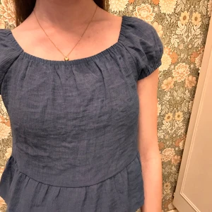 Blå blus med volangdetalj - Kortärmad blå blus volangdetalj i nederkant. Toppen är endast använd vid ett tillfälle och säljer för att den ej kommer till användning💗Storleken är 152 men skulle säga passar även xxs då jag vanligtvis bär xs. Den är en aning tight i ärmarna på mig, men ärmarna är stretchiga