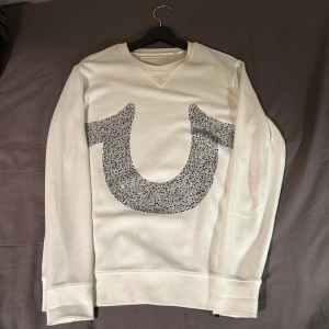 True Religion tröja - Säljer en true religion rhinestone tröja. Några stenar har fallit av men inte många, syns ej tydligt vid användning. dyr vid inköp runt 18/1900. Utöver ett par stenar som fallit av (bara att köpa på panduro och limma på nya) så är den superfint skick. Size XS men sitter mer som S beroende på önskad fit. 
