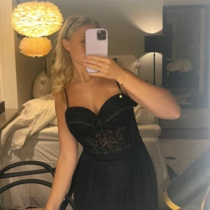 Balklänning - Säljer en elegant svart klänning med spetsdetaljer och smala axelband. Perfekt för festliga tillfällen! Klänningen har en åtsittande passform upptill och en lätt utsvängd kjol. Den är både stilren och bekväm, vilket gör den idealisk för en utekväll eller en fin middag.