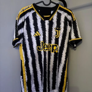 Juventus fotbollströja - Säljer en Juventus fotbollströja i svart och vitt med coolt randigt mönster. Tröjan har gula detaljer och korta ärmar. Perfekt för fans som vill visa sitt stöd på matchdagar! 🖤🤍💛självklart äkta nypris 1199 mitt pris 329