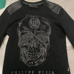  Philipp Plein tjock tröja med döskalle - Säljer en svart tröja från Philipp Plein med en stor, glittrig dödskalle på framsidan. Tröjan är köpt från johnells för några år sedan, påse till kommer inte kvitto