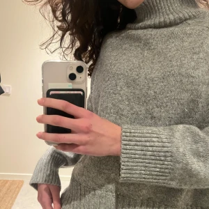 Grå stickad polotröja - Säljer en supermysig grå stickad polotröja. Perfekt för kyliga dagar med sin höga krage och långa ärmar. Tröjan har en ribbad design vid ärmslut och nederkant som ger en snygg passform. 