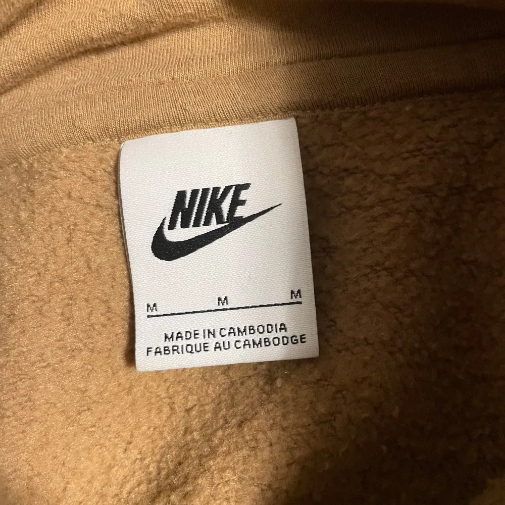 Säljer en snygg beige hoodie från Nike i storlek M. HELT NY SKICK! Aldrig använt. Den har en klassisk design med en känguruficka och justerbar huva. Perfekt för både vardag och en chill hemma kväll. Nike-loggan är broderad i vitt på bröstet. Dm om frågor och pris kan diskuteras!. Tröjor & Koftor.