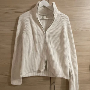 Vit stickad kofta från Monki - Säljer en superfin vit stickad kofta från Monki i storlek S. Dubbla dragkedjor och långa ärmar! Fjärde bilden är från hemsidan fast i annan färg 🤍