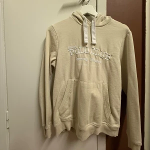 Ljus Beige hoodie från Polo Club🤍 - Säljer en snygg ljusbeige hoodie från Polo Club med fina vita detaljer. Den har en klassisk design med broderad text på framsidan och en mysig huva med dragsko. Den är oanvänd och har storlek S🥰