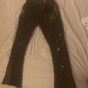 Svarta byxor från Gallery Dept. - Säljer ett par svarta byxor från Gallery Dept. med coola färgstänk för en unik look. Byxorna är i bomull och har en avslappnad passform. Perfekta för en casual stil med en twist. 