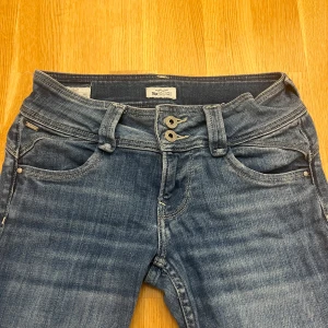 Blå jeans från Pepe Jeans - Säljer ett par snygga blå jeans från Pepe Jeans i bra skick. De har en klassisk femficksdesign och dubbla knappar i midjan. Perfekta för vardagsbruk och kan enkelt matchas med olika outfits. Passar både till skolan och fritiden! Passar dig som är mellan 165-168 är själv 166 lite långa på mig. Säljer då dem är lite stora. Skriv för fler bilder eller frågor❤️