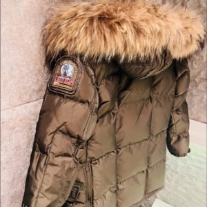 Brun dunjacka med päls från Parajumpers - Säljer en snygg brun dunjacka från Parajumpers med en fluffig pälsdetalj på huvan. Storlek 9-10 år 
