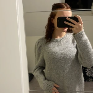 Grå stickad tröja med puffärmar - Säljer en supermysig grå stickad tröja med puffärmar. Perfekt för höst och vinter! Den har en rund halsringning och är i mycket bra skick. Passar perfekt för en avslappnad stil eller när du vill hålla dig varm och snygg. Nypris 500