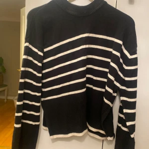 Svart och vit randig tröja - Säljer en snygg svart tröja med vita ränder. Den är långärmad och har en ribbad krage. Perfekt för höst och vinter, och den är i bra skick. Passar både till vardags och lite finare tillfällen.