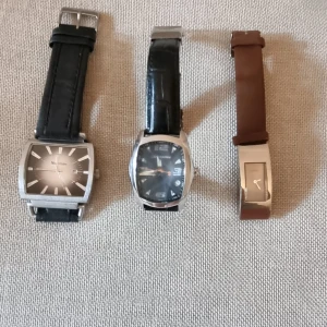 Klockor av olika märken  - 1. Märket är Moretime med fyrkantig urtalva, 27mm. Armband äkta läder Pris: 50kr  2. Märket är Chronotech med fyrkantig urtavla, 18mm. Armband äkta läder, ormmönstrad Pris: 50kr   3. Guess klocka, svart urtavla, 5mm. Armband i brun mocka Pris: 75 kr 