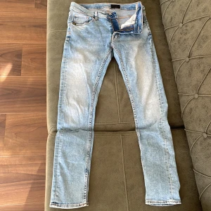 Ljusblå jeans från Tiger of Sweden - Säljer ett par snygga ljusblå jeans från Tiger of Sweden. De har en slim passform och är i storlek W30 L32. Jeansen har en klassisk femficksdesign och stängs med dragkedja och knapp. Perfekta för både vardag och fest!