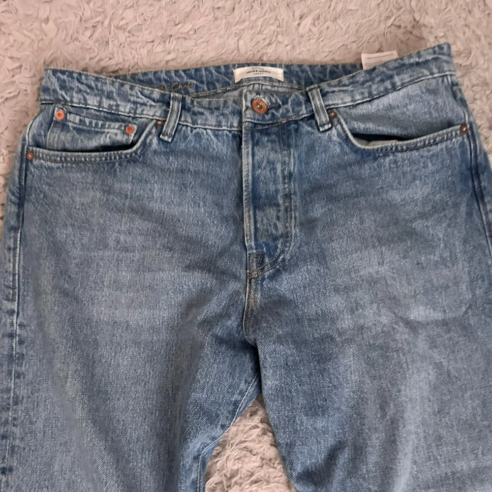 Säljer ett par snygga blå jeans från Jack & Jones. De har en relaxed fit och är perfekta för en avslappnad stil. Nypriset på de är 800kr. Jeansen har en klassisk femficksdesign och en knappgylf. De är i bra jätteskick och redo för en ny ägare!. Jeans & Byxor.