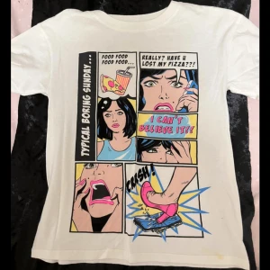 Vit t-shirt med serietidningstryck - Säljer en vit t-shirt med ett coolt serietidningstryck på framsidan. Trycket har en popkonststil med färgglada rutor. Perfekt för en avslappnad look eller för att ge lite humor till vardagen. T-shirten är kortärmad och i bomull. 