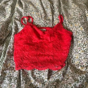 Röd spetslinne från FB Sister - Säljer ett supergulligt rött spetslinne från FB Sister. Det är axelbandslöst och perfekt för sommaren. Linnet är i storlek XS och har en fin blommig spetsdesign. Perfekt för en fest eller en varm sommardag! 🌺