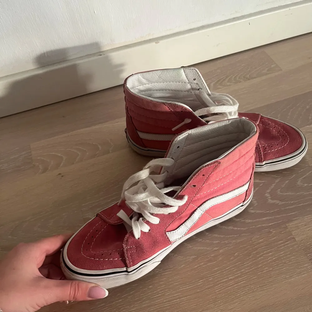 Säljer ett par snygga rosa och vita Vans sneakers i storlek dam 39. De har en klassisk hög modell med snörning och den ikoniska vita sidoremsan. Skorna är i bra skick och perfekta för både vardag och fest. Passar till alla dina outfits!. Skor.