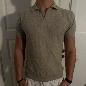 Beige Pikétröja från Oscar Jacobson - Säljer en stilren beige pikétröja från Oscar Jacobson. Tröjan har en klassisk krage och korta ärmar, perfekt för en avslappnad men ändå uppklädd look. Passformen är normal och den är i nyskick. Storlek S. Modellen är 182 cm och väger 75 kg. Pris går att diskuteras!