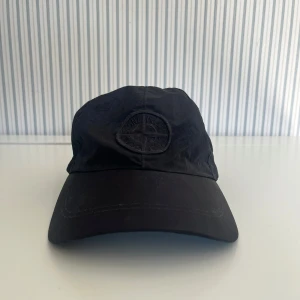 Stone island keps - Snygg svart stone island keps, nästan aldrig använd och felfri från smuts och inga trasiga sömmar. Nu pris 1700 kr, mitt pris 800 kr