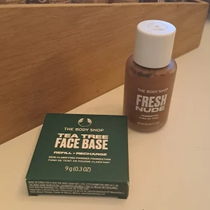 Foundation och Face Base från The Body Shop - Säljer två produkter från The Body Shop. Först har vi 'Fresh Nude Foundation' i en 30 ml flaska, perfekt för en naturlig look. Sedan har vi 'Tea Tree Face Base', en puderfoundation med tea tree-olja, i nyansen Deep 2C. Båda produkterna är veganska och innehåller naturliga ingredienser. Perfekt för dig som vill ha en fräsch och jämn hudton!