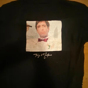 Svart Scarface t-shirt från Pull&Bear - Säljer en svart t-shirt från Pull&Bear med Scarface-tema. Lite sliten på Tony Montana loggan (pris kan diskuteras vid snabb affär)