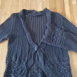 Grå stickad kofta från KappAhl - Säljer en snygg grå stickad kofta från KappAhl. Koftan har långa ärmar och knappar framtill. Den har ett fint stickat mönster som ger en extra touch. Perfekt för kyligare dagar🌚