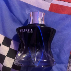 Silenzia for Men Parfym - Elegant herrparfym i en stilren svart flaska med silverfärgad kork. Flaskan har en unik, kurvig design som ger ett lyxigt intryck. Perfekt för den som söker en sofistikerad doft. Och det finns mycket kvar i den. Kika gärna in på min profil o kolla va jag säljer mer🙃