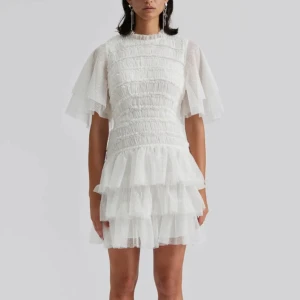 Vit klänning med volanger, studentklänning  - Säljer en söt vit klänning från By Malina med volanger och korta ärmar. Klänningen har en smockad överdel och flera lager av volanger i kjolen, modellen är Minnie miniklänning. Perfekt för studenten eller midsommar! 🌸Klänningen är aldrig använd (bara testad) och har lappen kvar! Priset kan diskuteras!💗Nypris: 3800 kr