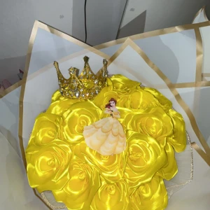 Gul rosbukett med prinsesskrona och figur - En vacker bukett av gula rosor i satin, dekorerad med en glittrande prinsesskrona och en figur av en prinsessa i gul klänning. Perfekt som en fantasifull och färgglad dekoration.350kr+ frakt 
