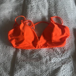 Orange bikiniöverdel - Snygg orange bikiniöverdel med smala axelband och en enkel design. Perfekt för soliga dagar på stranden eller vid poolen. Den har en stilren look som är lätt att matcha med olika underdelar.