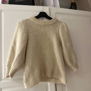 Beige stickad tröja - Mysig beige stickad tröja med långa ärmar och ribbade detaljer vid hals, ärmslut och nederkant. Perfekt för kyliga dagar och ger en avslappnad stil. Passar bra till jeans eller kjol för en bekväm look.