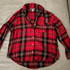 Röd rutig skjorta från Victoria's Secret - Säljer en snygg röd och svart rutig skjorta från Victoria's Secret. Skjortan har långa ärmar och knappar framtill. Perfekt för en avslappnad stil med en touch av klassisk charm. 🖤