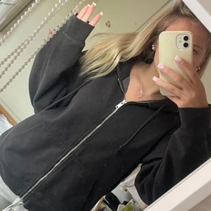 Svart hoodie med dragkedja - Säljer en svart hoodie med dragkedja framtill. Den har en avslappnad passform och långa ärmar. Perfekt för en bekväm och stilren look. Från brandy melville