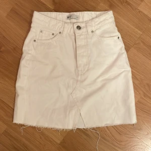 Vit jeanskjol från Gina tricot - Snygg vit jeanskjol från Gina tricot i storlek 34. Kjolen har som en lite sliten kant längst ner men det är designen. Jag säljer den pågrund av att den sitter lite för tajt i midjan.💗