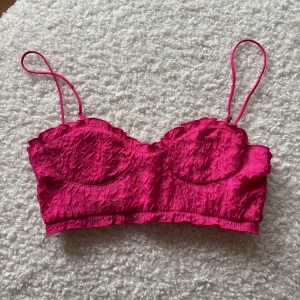 Rosa korsett från Zara - Snygg rosa korsett från Zara med tunna axelband och en texturerad yta. Perfekt för att ge en färgklick till din outfit. Den har en smickrande passform och är lätt att matcha med olika stilar.