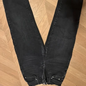 Svarta jeans från Gina Tricot - Snygga svarta jeans från G Perfect med en klassisk design. De har en rak passform och är perfekta för en stilren look. Jeansen har fickor både fram och bak samt en dragkedja och knapp framtill.