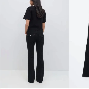 Svarta lågmidjade bootcut jeans - Snygga svarta bootcut jeans med klassisk femficksdesign och knappgylf. Perfekta för en stilren look, dessa jeans har en smickrande passform och är tillverkade i ett bekvämt material.