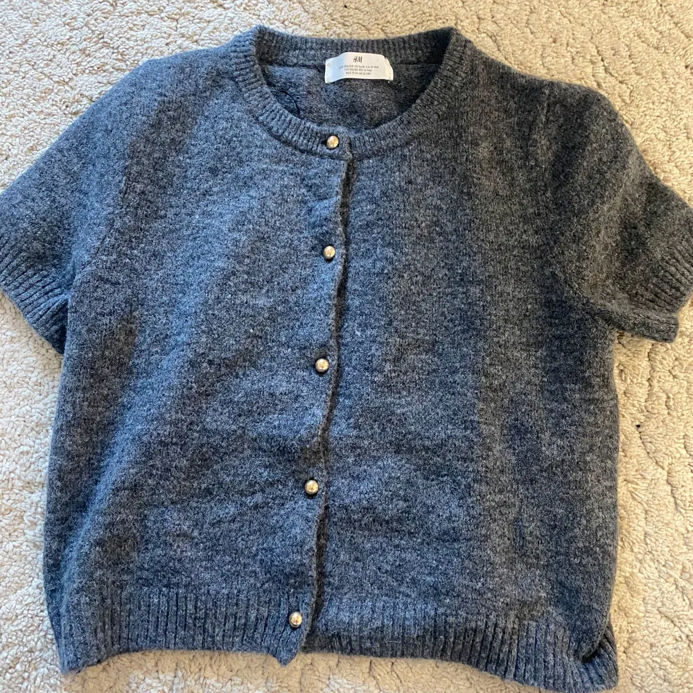 Säljer en stilren grå kofta från H&M med knappar framtill. Koftan är tillverkad i en mjuk blandning av polyester, akryl och ull, vilket gör den både bekväm och varm. Perfekt för lager-på-lager under kyligare dagar🩵. Neuletakit & Villapaidat.