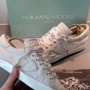 Vita sneakers från Philippe Model - Stilrena vita sneakers från Philippe Model med snörning och en diskret logga på sidan.  Har knappast använt dem. Har lådan och äkthetsbevis. 