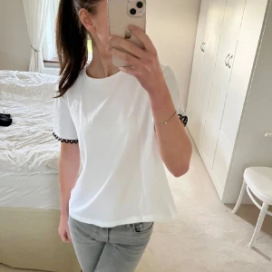 Vit t-shirt  - En snygg vit T-shirt med svarta detaljer vit ärmarna från Zara.