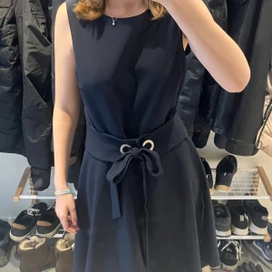 klänning från Mint & Berry  - Snygg mörk blå ärmlös klänning från Mint & Berry med knytband i midjan. Perfekt för en stilren look. Klänningen har en klassisk design som passar till många tillfällen, använd få gånger💗