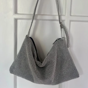 Väska i silverfärgad strass - Afton/Fest-väska i silverfärgad strass med tillhörande axelrem  Längd 32 cm  bredd 18 cm 