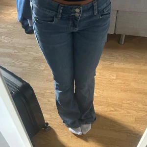 Low waist blå jeans med broderade fickor - Säljer ett par snygga blå jeans med broderade detaljer på bakfickorna. De har är bootucut och lågmidjade. Använda Max 3 gånger så i nytt skick. 