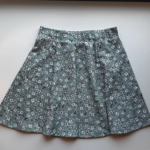 Mintgrön kjol - Mintgrön kjol med vita blommor. Resår i midjan och stretchigt tyg. Är något nopprig på baksidan (inget som syns, bara känns), men annars bra skick. 