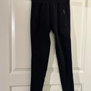 Svarta leggings - Säljer ett par svarta leggings i bra skick. De är högmidjade och har en tight passform, perfekta för både träning och vardagsbruk. Materialet är mjukt och stretchigt, vilket gör dem superbekväma att ha på sig. Se tillhörande topp för komplett sett.